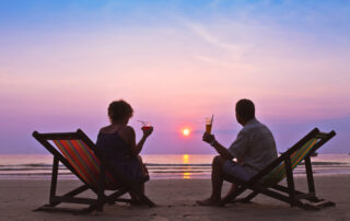 Mann und Frau sitzen am Strand und trinken Cocktails
