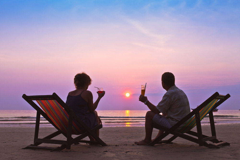 Mann und Frau sitzen am Strand und trinken Cocktails